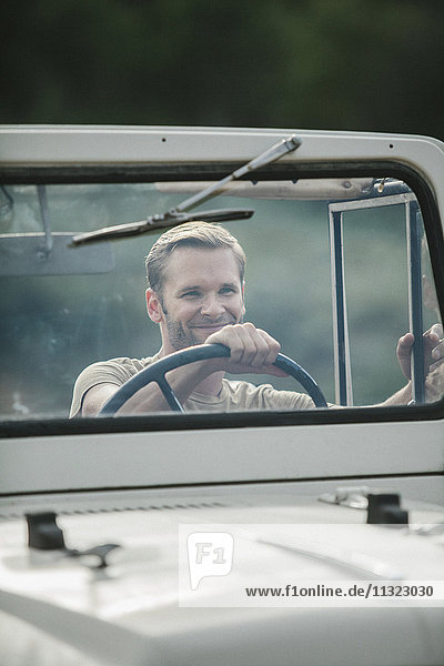 Ein Mann am Steuer eines Jeeps mit offenem Verdeck.