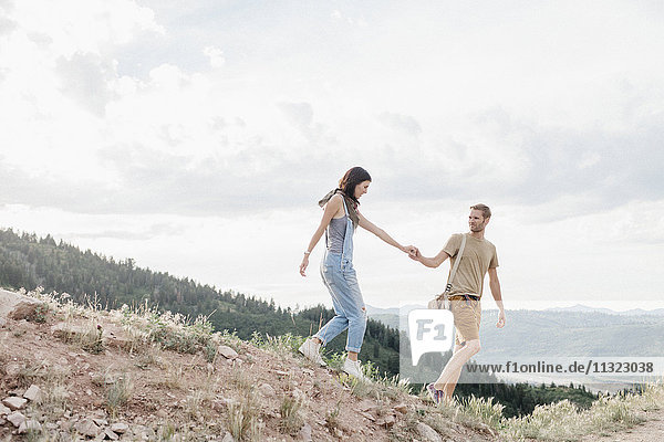 Ein Paar in den Bergen  das Hand in Hand geht.