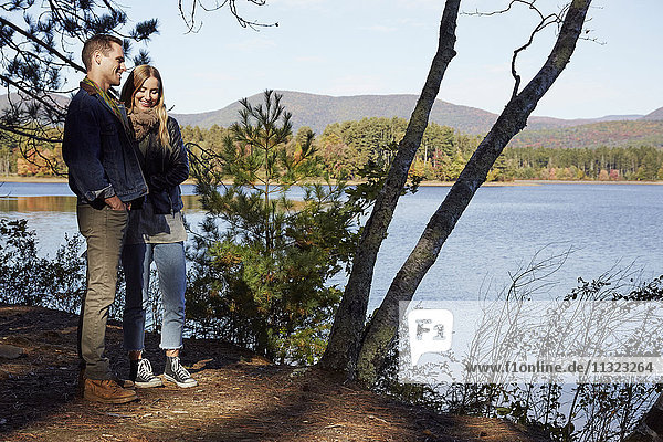 Two people on the shore of a lake in autumn.