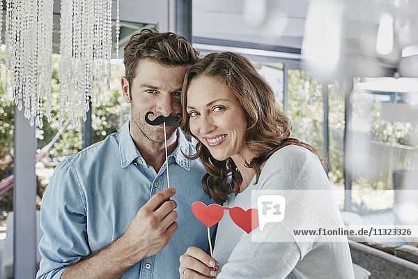 Couple with paper moustache and heart-shaped eye disguise