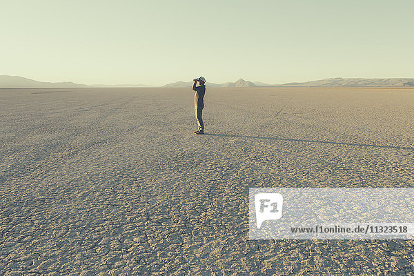 Man standing in remote desert  looking through binoculars  Black Rock Desert  Nevada
