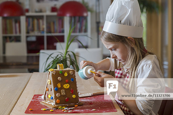 Girl garnishing gingerbread house