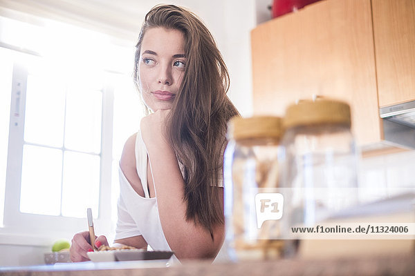 Young woman in kitchen thinking