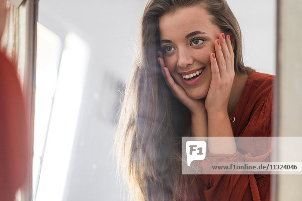 Spiegelbild einer glücklichen jungen Frau  die sich selbst ansieht.