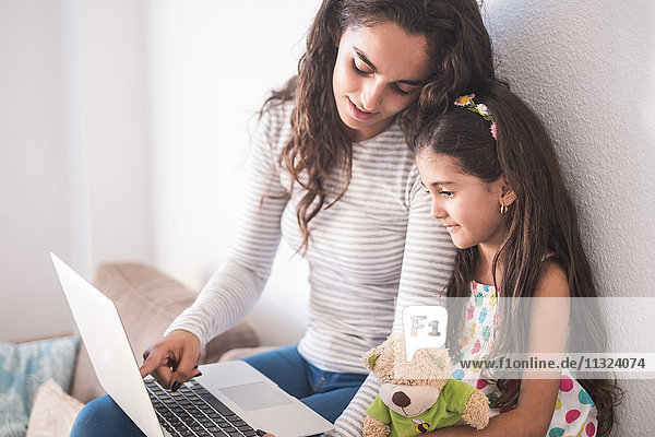 Teenager Mädchen und ihre kleine Schwester mit Laptop