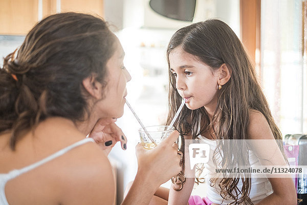 Teenagermädchen und ihre kleine Schwester in der Küche bei einem Drink