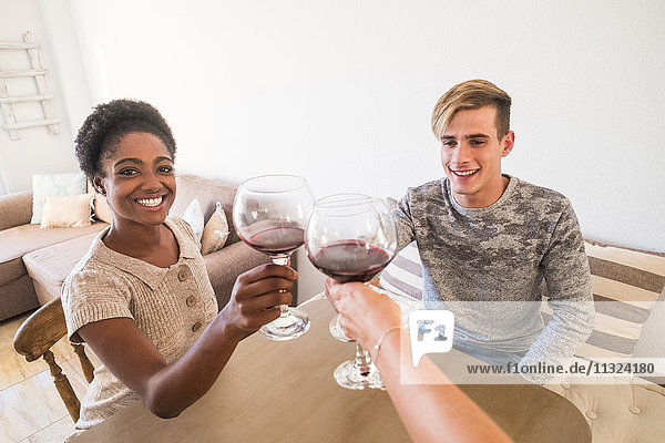 Junges Paar  das zu Hause mit Rotwein toastet.