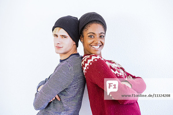 Portrait des jungen Paares Rücken an Rücken vor weißem Hintergrund