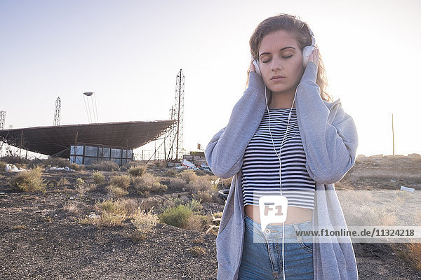 Spanien  Teneriffa  junge Frau in der Nähe eines verlassenen Flughafens mit Kopfhörern