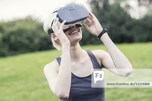 Smiling young woman using Virtual Reality Glasses outdoors
