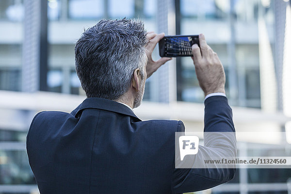 Geschäftsmann im Freien beim Fotografieren von Mobiltelefonen