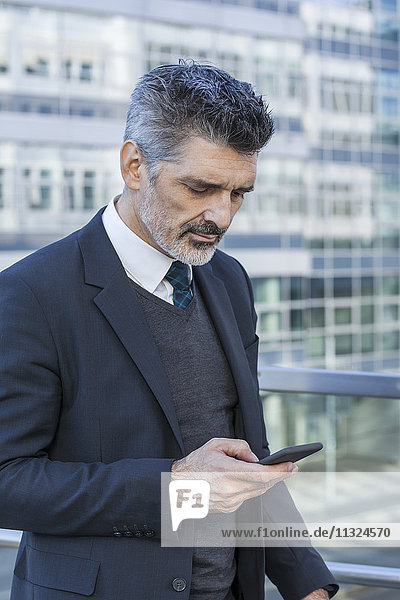 Businessman outdoors looking on cell phone
