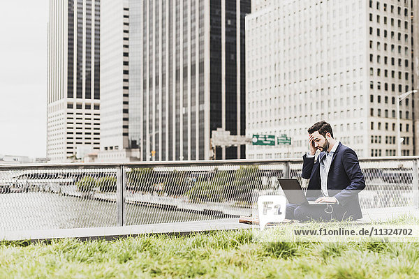 USA  New York  Manager in Manhattan sitzend im Freien  mit Laptop und Kopfhörer