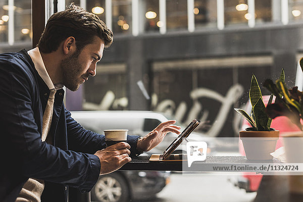 USA  New York City  Geschäftsmann sitzend im Coffee Shop  mit digitalem Tablett
