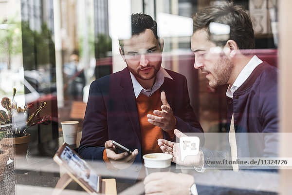 USA  New York City  Businessmen meeting in coffee shop  using mobile devices