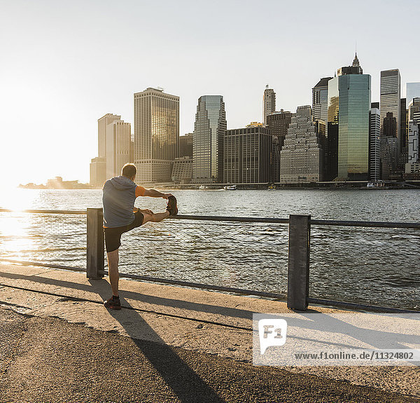 USA  Brooklyn  Mann beim Stretching vor der Skyline von Manhattan am Abend