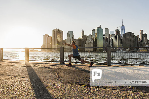 USA  Brooklyn  Mann beim Stretching vor der Skyline von Manhattan am Abend