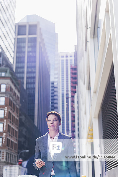 USA  New York City  Geschäftsfrau in Manhattan mit Handy und Kopfhörer