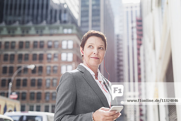 USA  New York City  Geschäftsfrau in Manhattan mit Handy und Kopfhörer