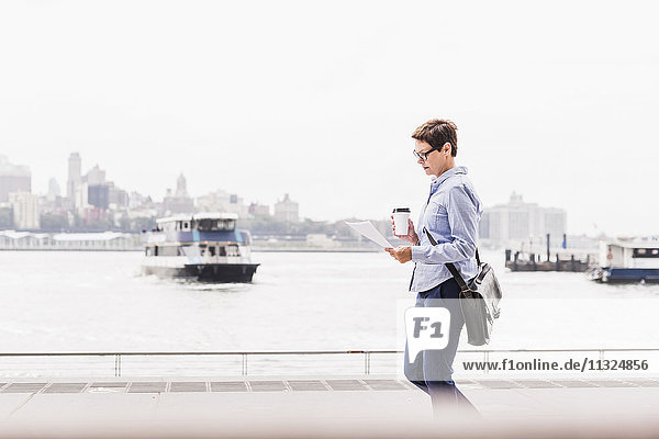 USA  New York City  Geschäftsfrau beim Spaziergang am East River Lesedokument