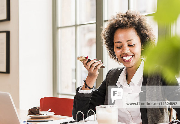 Smiling young woman using cell phone in a cafe