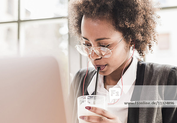 Young woman with laptop drinking Latte Macchiato