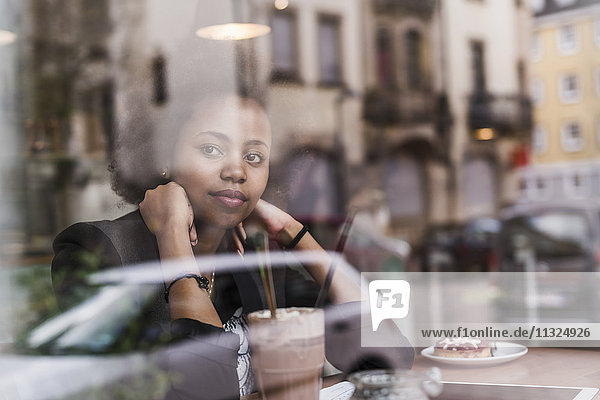 Junge Frau in einem Café mit Blick aus dem Fenster