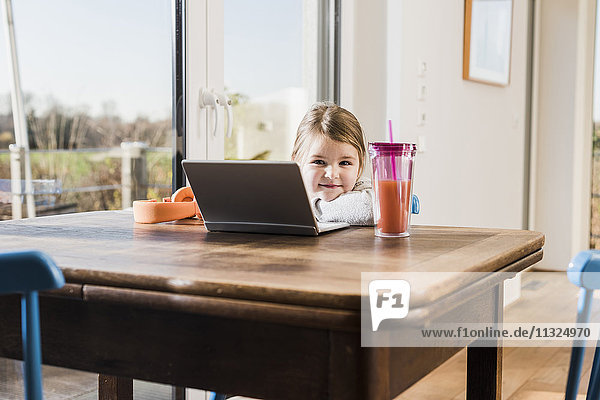 Little girl sitting at home using laptop