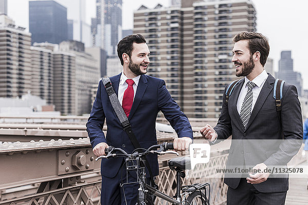 USA,  New York City,  zwei Geschäftsleute mit Fahrrad auf der Brooklyn Bridge