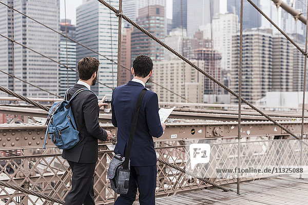 USA,  New York City,  zwei Geschäftsleute an der Brooklyn Bridge