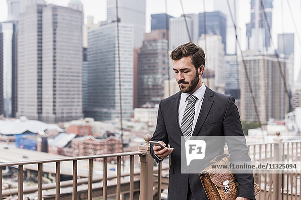 USA  New York City  Geschäftsmann auf der Brooklyn Bridge per Handy