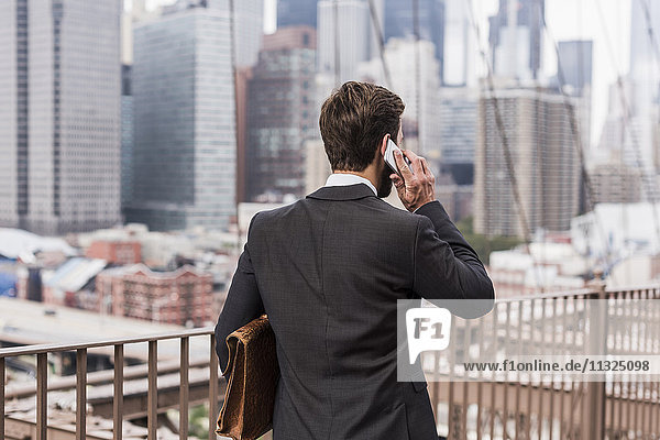 USA  New York City  businessman on Brooklyn Bridge talking on cell phone