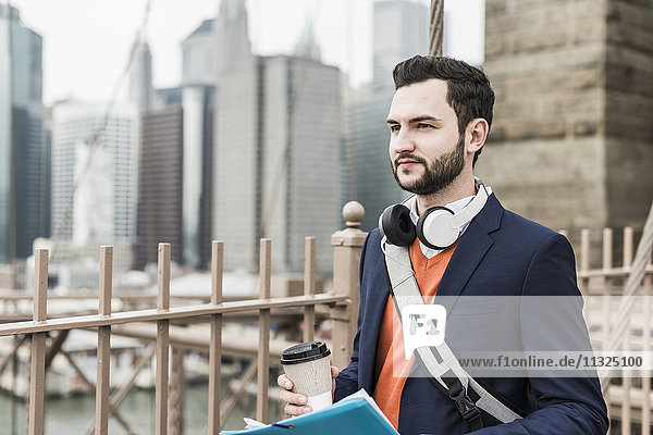 USA  New York City  Mann auf der Brooklyn Bridge mit Kaffee zum Mitnehmen