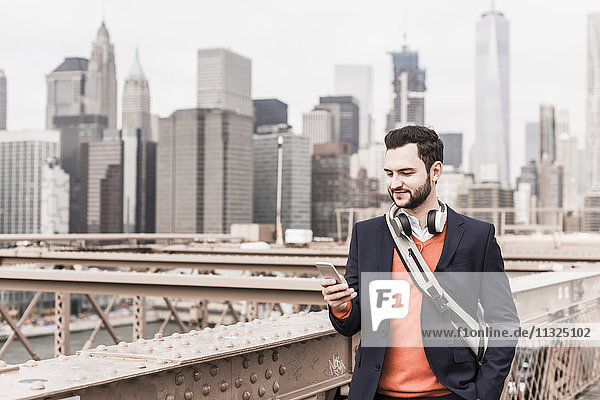 USA  New York City  man on Brooklyn Bridge using cell phone