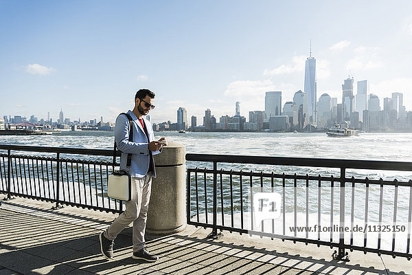 USA  Mann mit Handy an der New Jersey Waterfront mit Blick auf Manhattan