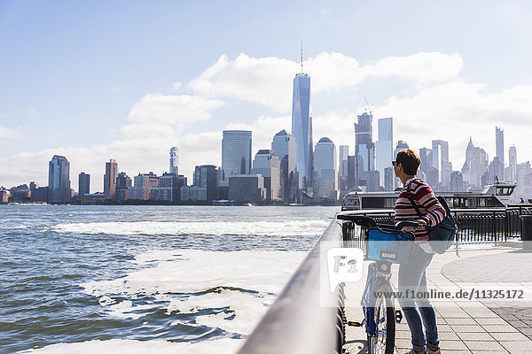 USA  woman with bicycle at New Jersey waterfront with view to Manhattan