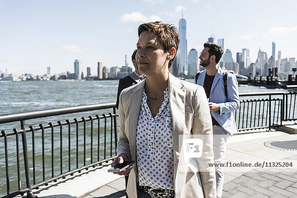 USA  Geschäftsfrau mit Handy am New Jersey Waterfront mit Blick auf Manhattan