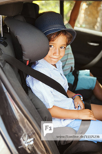 Portrait of smiling little boy sitting on backseat of a car