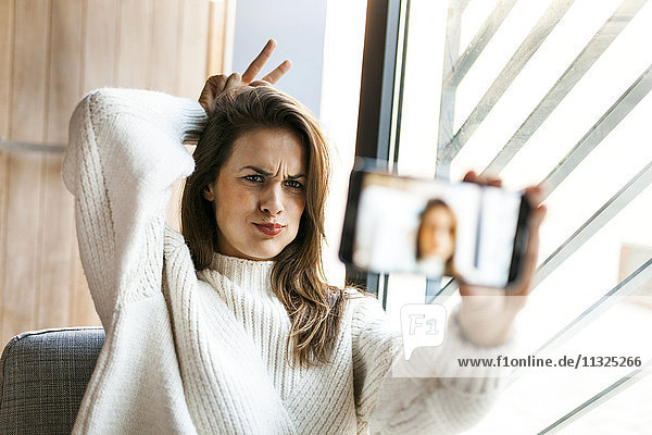 Verspielte junge Frau nimmt einen Selfie mit Handy