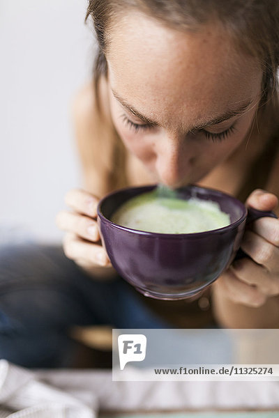 Woman drinking matcha latte at home