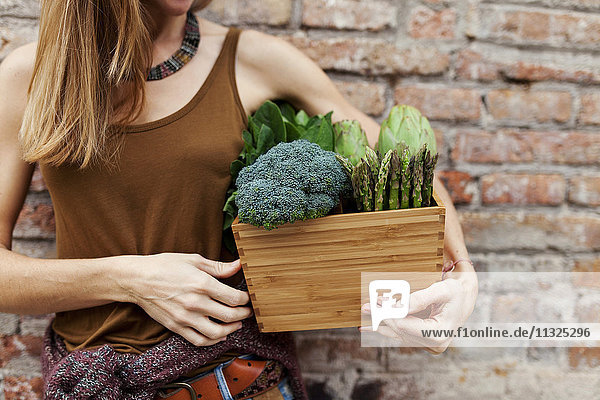 Frau hält Korb mit frischem Gemüse