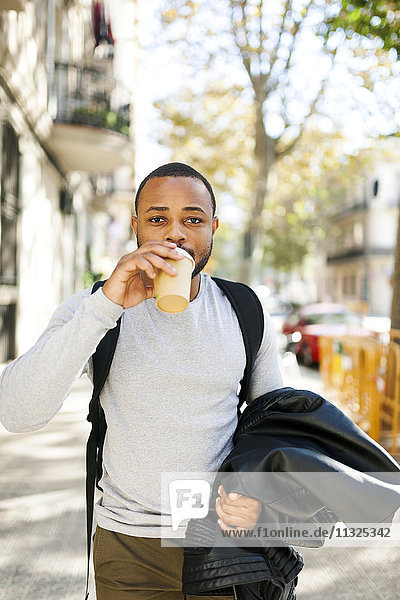 Portrait of young man with coffee to go