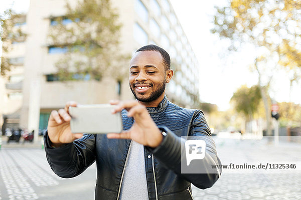 Smiling young man taking selfie with smartphone