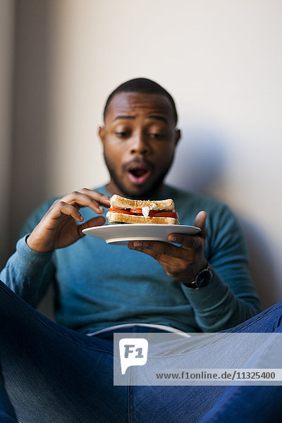 Young man eating a club sandwich