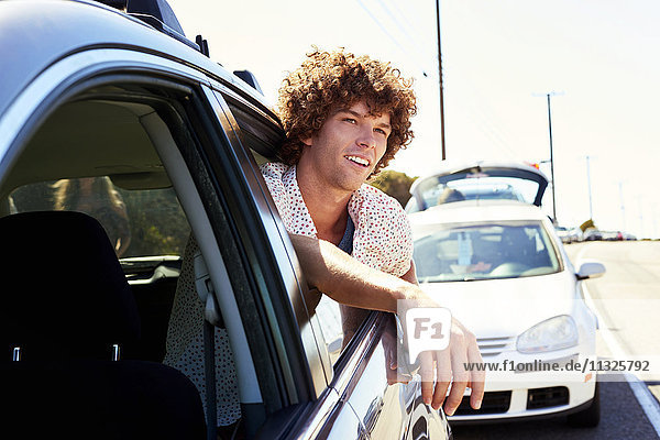 Smiling young man looking out of car window