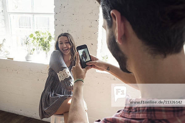 Fröhliche junge Frau posiert für eine Handy-Aufnahme