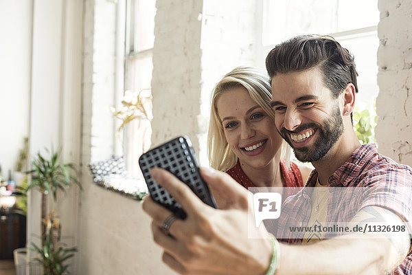 Glückliches junges Paar  das einen Selfie in einem Loft nimmt.