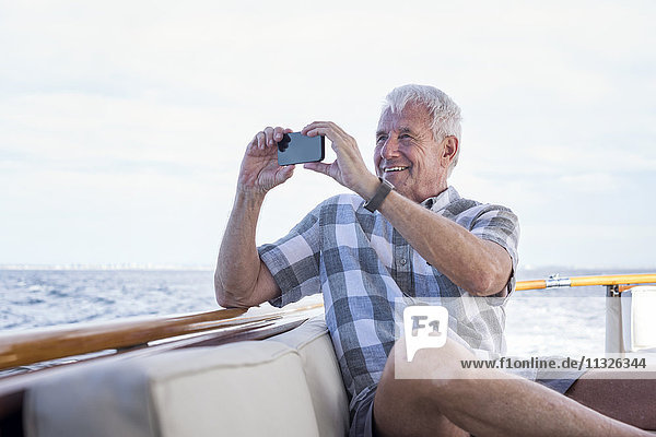 Ein älterer Mann auf einer Bootsfahrt  der ein Foto macht.