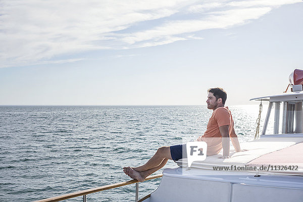 Junger Mann auf einem Boot sitzend