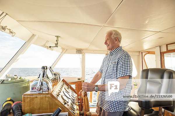 Zuversichtlicher Senior steuert ein Boot